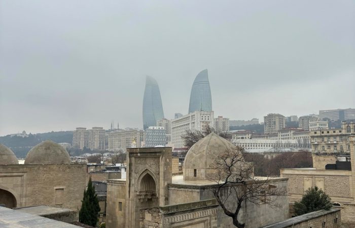Picture from Baku. There is old building in the front of the picture and far on the background there is two skyscrapers.