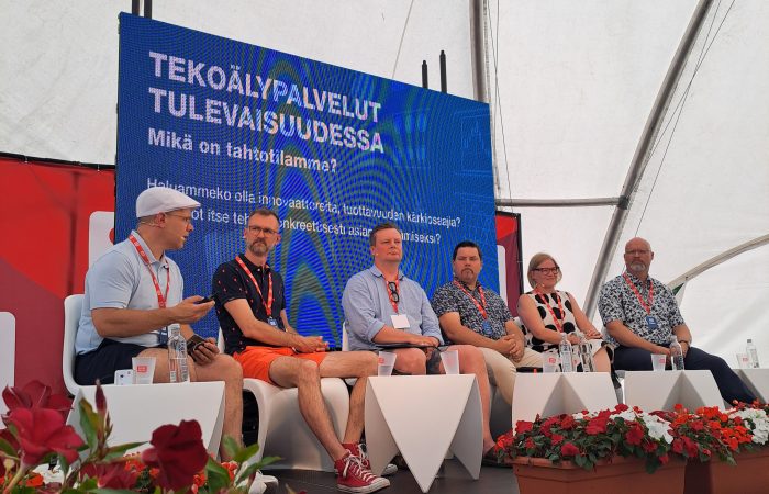 Lavalla istuu kuusi henkilöä keskustelemassa.