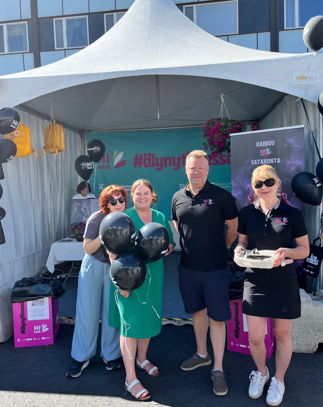 Kuvassa neljä hymyilevää henkilöä yhteiskuvassa.