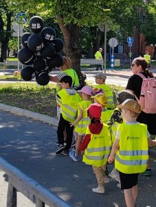 Kuvassa joukko pieniä lapsia huomioliivit päällä kävelemässä aikuisten johdolla.