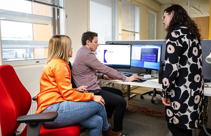 Kolme ihmistä katselee yhdessä tietokoneelta dataa.