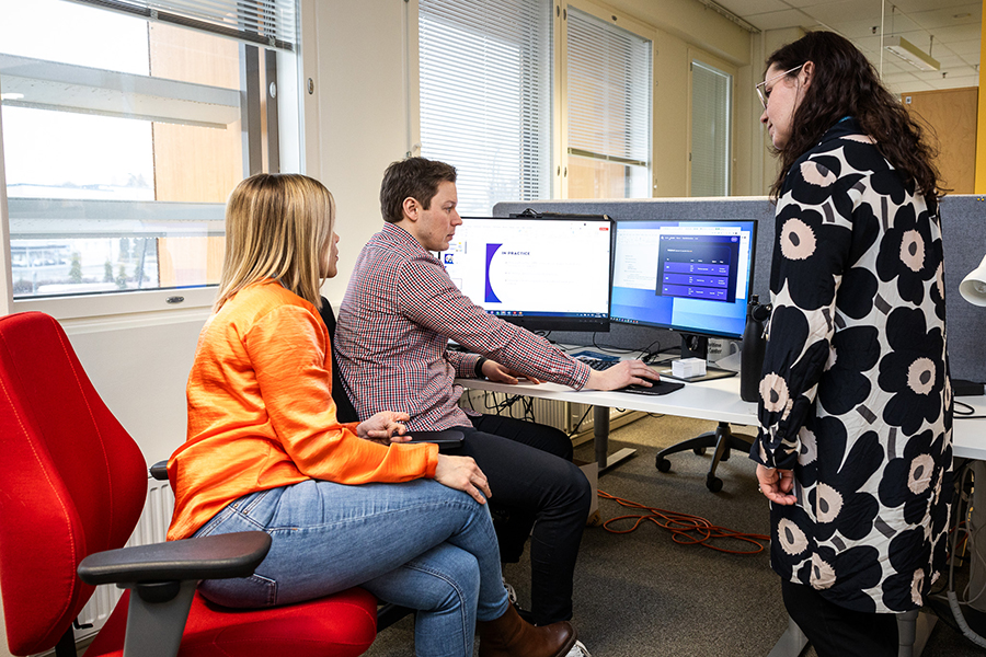 Kolme ihmistä katselee yhdessä tietokoneelta dataa.