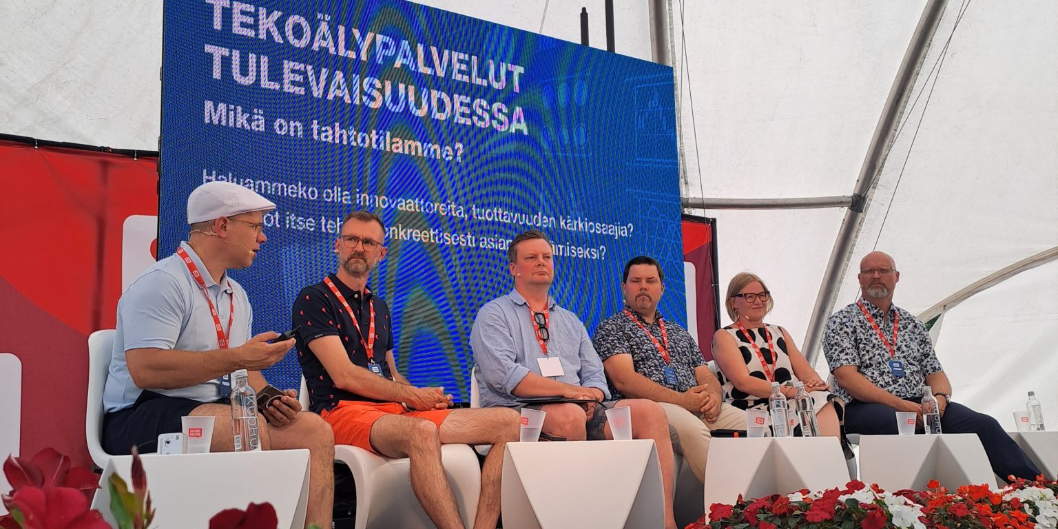 Lavalla istuu kuusi henkilöä keskustelemassa.