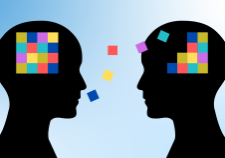 Kaksi ihmishahmon siluettia vaihtamassa värikkäitä palikoita päänsä välillä, kuvaten ajatusten tai tiedon siirtymistä.