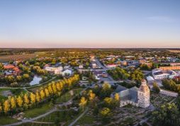 Ilmakuva Huittisista auringonlaskussa: kirkko ja hautausmaa etualalla, ympärillä pientaloja, puistoja ja peltoja.