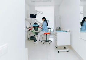 Hammashoitohuone, jossa suojavaatteisiin pukeutunut työntekijä istuu hoitotuolin vieressä.