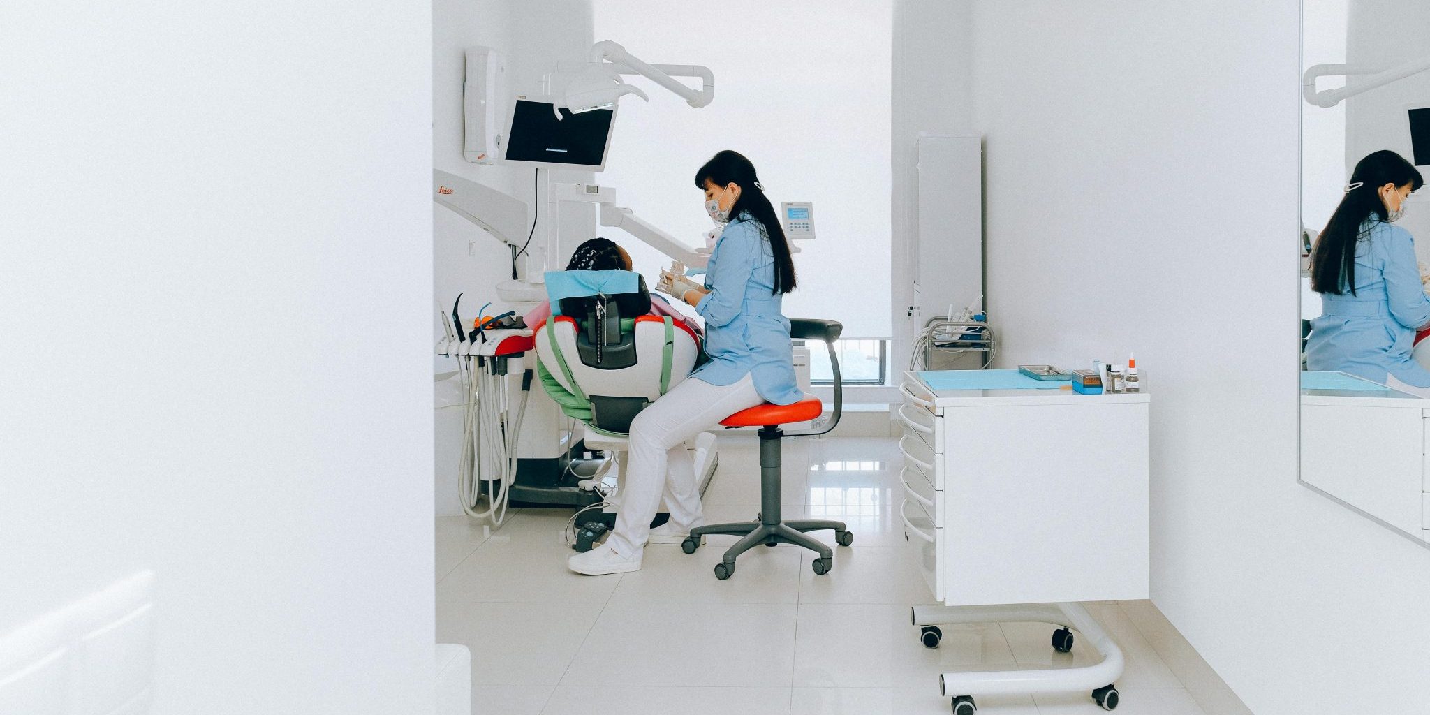 Hammashoitohuone, jossa suojavaatteisiin pukeutunut työntekijä istuu hoitotuolin vieressä.