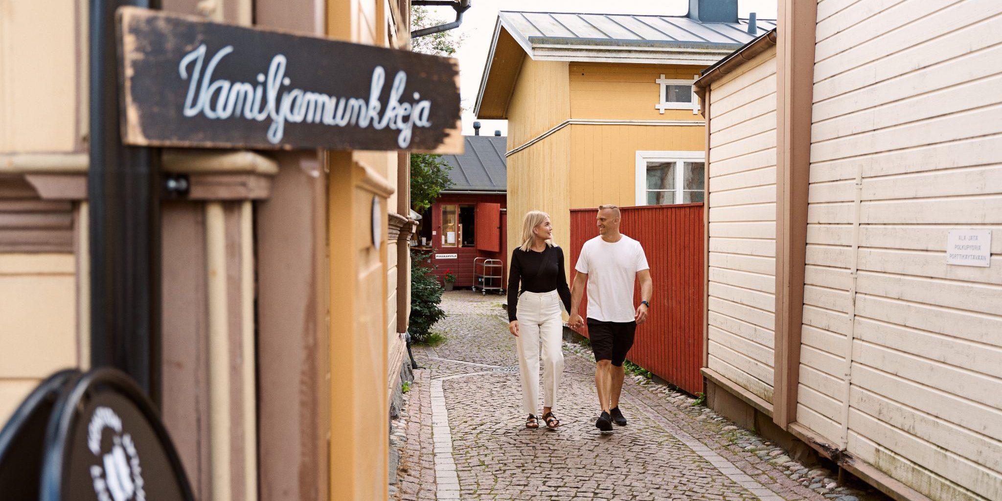 Vanhan Rauman mukulakivikatu ja kävelijöitä puutalojen välissä.