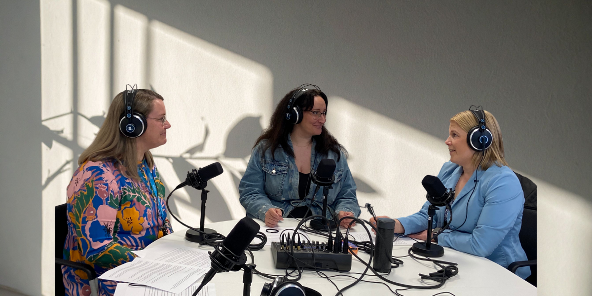 Petra Sippola, Mari Viljanen ja Minttu Porri istuvat pyöreän pöydän äärellä. Kaikilla on podcastiin tarvittavat kuulokkeet ja mikrofoni.
