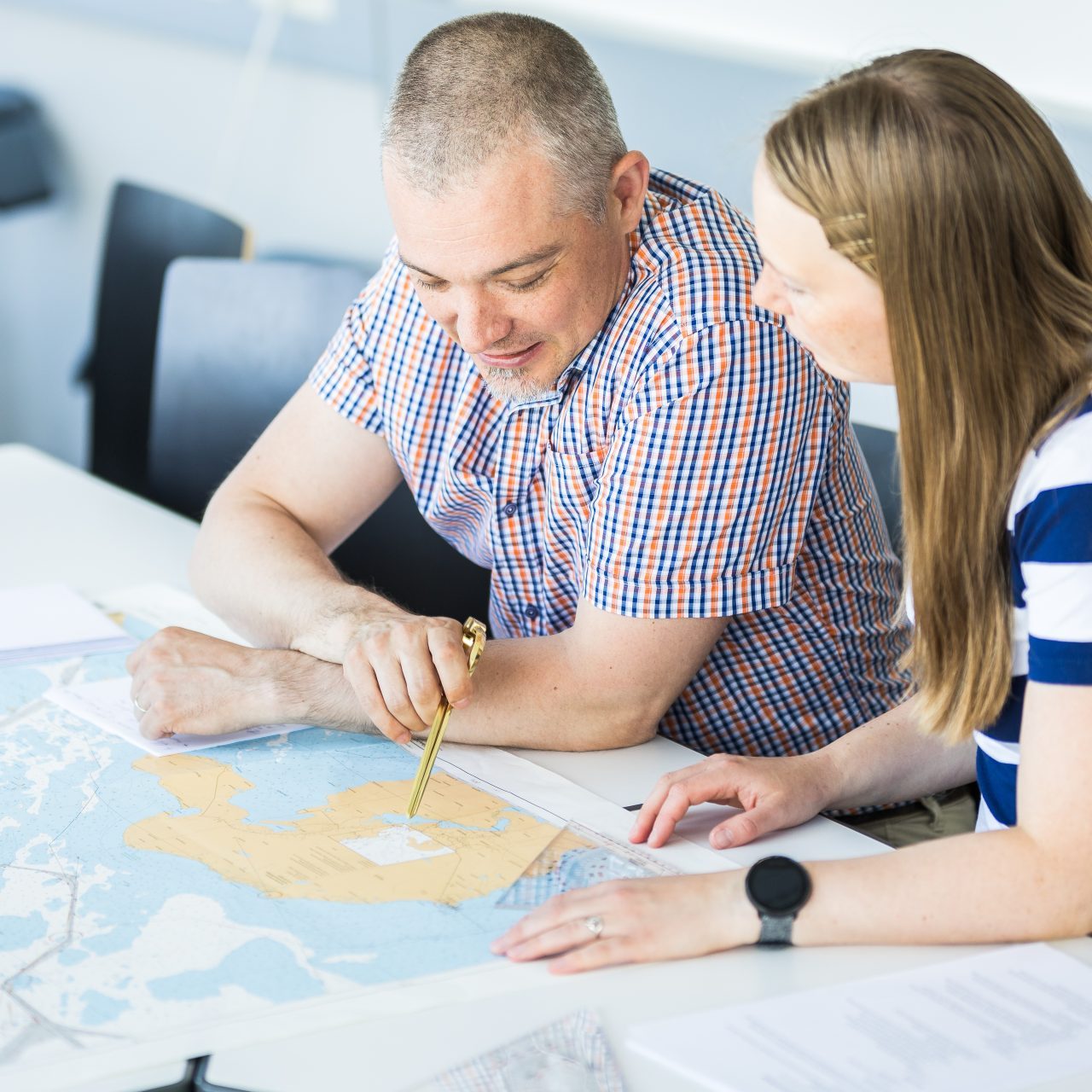 Kaksi henkilö tutkii merilokeja pöydän ääressä.