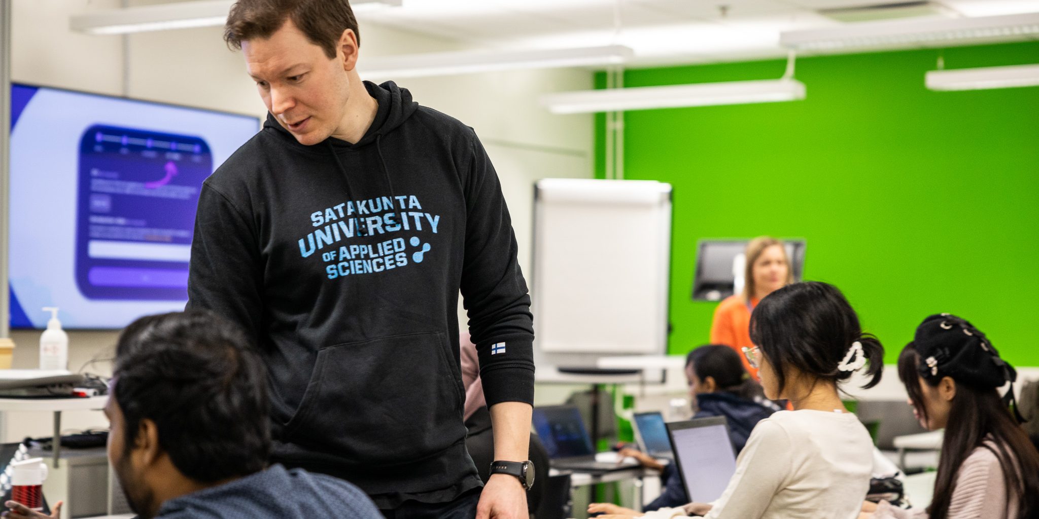 Henkilö seisomassa istuvien henkilöiden keskellä ja kädellä ohjeistamassa.