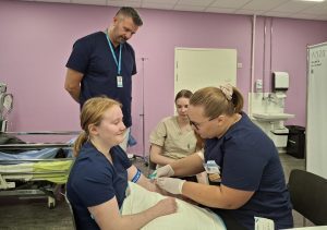 Terveydenhuollon opiskelijoita harjoittelemassa verinäytteenottoa luokkatilassa.